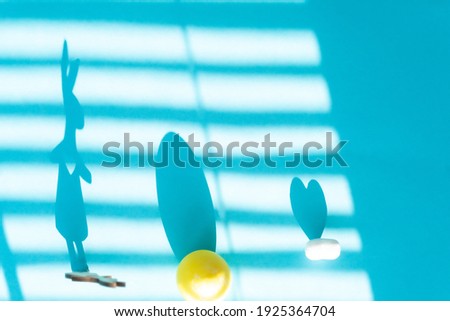 On a blue background shadow from the blinds,  of the Easter bunny, egg and heart.