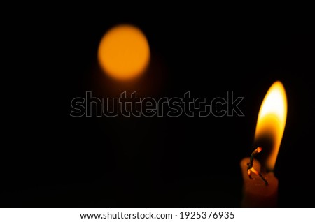 Close-up​ burning candle light on dark background​ with orange​ spot 