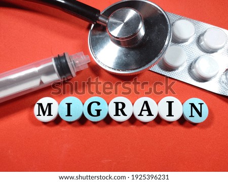 Selective focus. Word MIGRAIN on medicine with sryinge and stethoscope on red background. Medical concept.