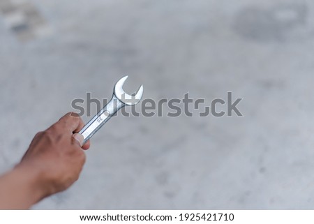 A mechanic with a hand holding a wrench