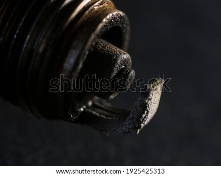 A macro photo of the contacts of a faulty car spark plug, on a black background.