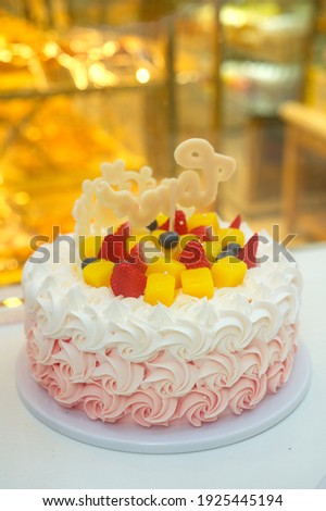 Birthday cake decorated with flower-shaped cream sold in a cake shop, with mango, strawberry and blueberry on the cake, vertical picture