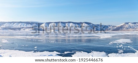 Baikal Lake in winter. Panorama of the frozen Small Sea Strait on a sunny frosty February day. View of the Sarma gorge and snow-capped mountains. Focus in the center of the panorama
