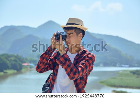 Young Asian travel photographer taking pictures outdoors
