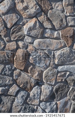 irregular stones on stone wall of exterior building textured background outdoors vertical format