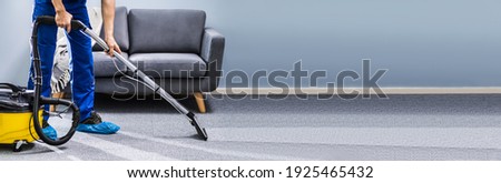 Male Janitor Cleaning Carpet With Vacuum Cleaning In The Living Room Royalty-Free Stock Photo #1925465432