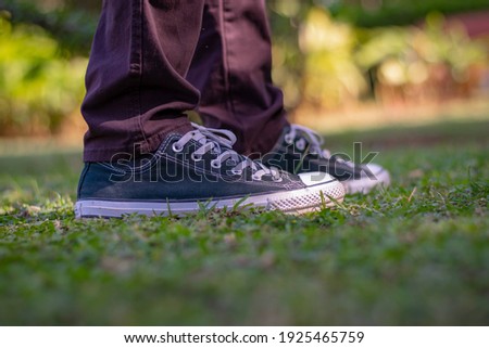 man standing on grass wearing canvas shoes 