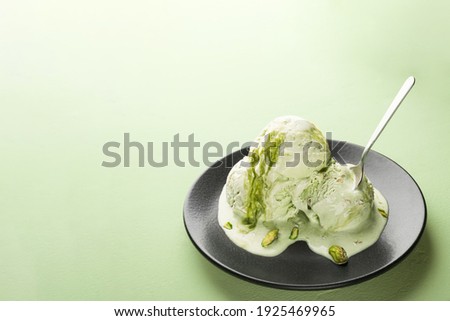 Melted balls of pistachio ice cream in a plate with copy space.