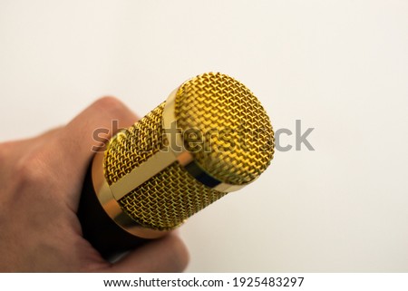 A hand holding Golden Studio Microphone on the white background for Podcast