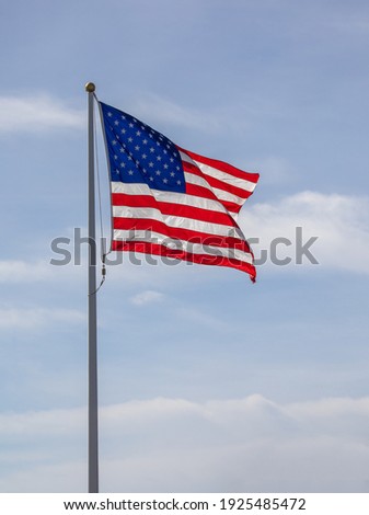 The American flag against a blue sky with clowds.