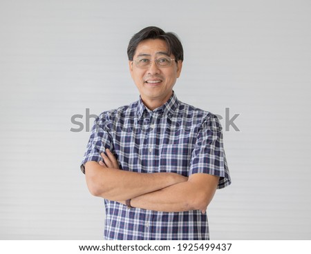 Portrait close up shot of middle aged asian male model with short black hair wearing blue plaid shirt with stand smiling fold his arms in smart pose on white background. Royalty-Free Stock Photo #1925499437