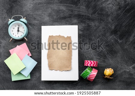 White blank cards, an alarm clock, and colored stickers on a black background-top view.