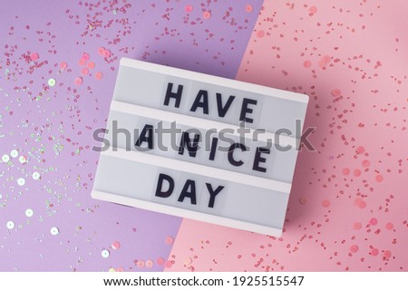 Have a nice day - text on display lightbox on purple and pink background.