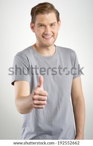 Young man gesturing OK sign on light background