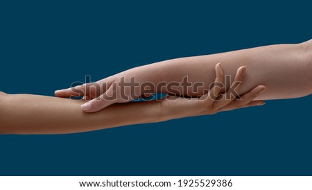 Close up of two women holding each other arm isolated on blue background. Support, togetherness concept