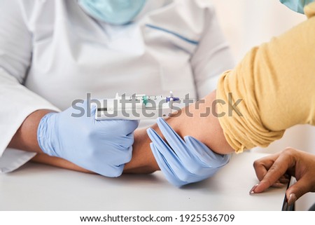 Medicine is the best medication. Scaled up look on a female medical professional wearing gloves holding an arm of a young patient while vaccinating him. Covid 19 concept. Stock photo