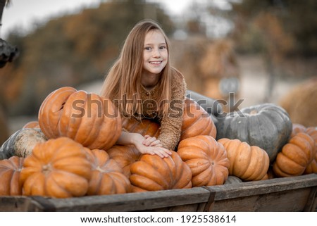A girl lies on a trolley with ripe pumpkins