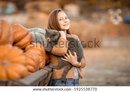 A girl holds a black cat in her arms.