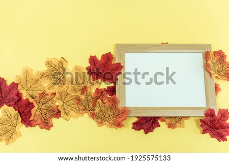 Blank wooden frame on yellow background with autumn leaves. Flat lay. Copy space. Top view