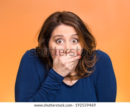 Closeup portrait beautiful, middle aged shocked young woman, covering her mouth, wide open eyes, isolated orange background. Negative human emotion, facial expression, feeling, signs, symbol, reaction