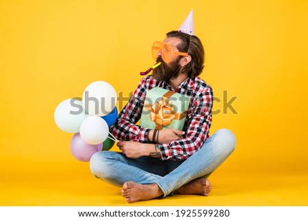 anniversary. have a happy holiday. party time. happy birthday to you. bearded mature man celebrate birthday party. cheerful man in bday hat hold holiday balloons. gifts and presents concept.