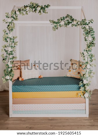 Handmade Montessori bed in a photo studio with white roses and eucalyptus