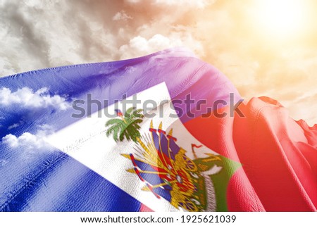 Haiti national flag cloth fabric waving on beautiful grey sky.