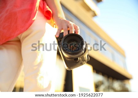 Young photographer with professional camera outdoors, closeup. Space for text