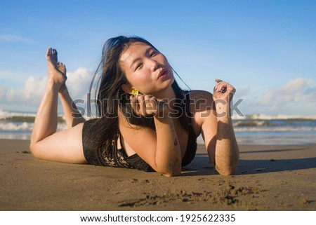 beautiful Asian woman enjoying beach holidays - young happy and attractive Korean girl in bikini posing playful at tropical beach during Summer vacation in travel concept