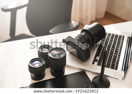 Photographer's workplace with a modern equipment. Mirrorless camera, laptop and prime lenses. Royalty-Free Stock Photo #1925625812