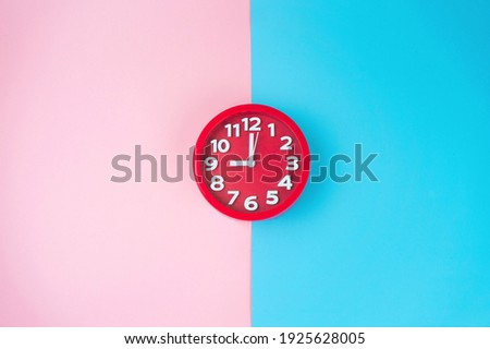 Alarm clock isolated on pink and blue background with copy space
