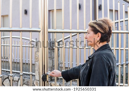 Woman opening chrome gate. Stainless steel fence