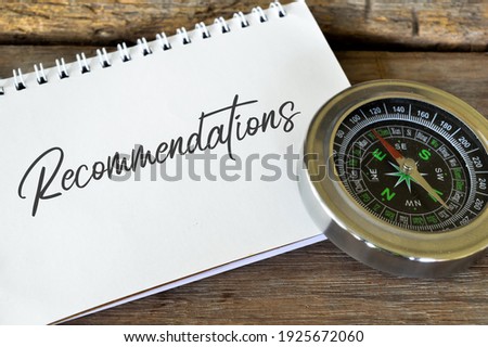 Compass and notebook written with text RECOMMENDATIONS over wooden background.