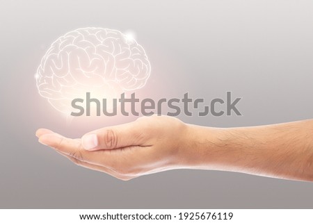 Man holding brain illustration against gray wall background. Concept with mental health protection and care.	 Royalty-Free Stock Photo #1925676119