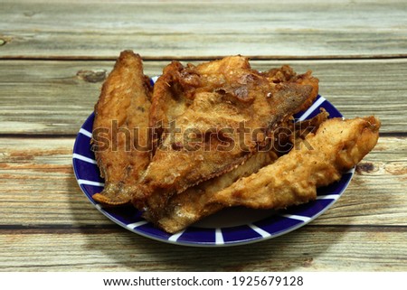Pile of deep fried Grouper fish fillet (Sea basses) seasoning with flour and pepper serving on the plate. 
