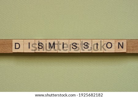 gray word dismission made of wooden square letters on green background