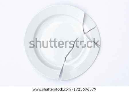 shards of a broken white plate stacked together on a white background. The concept of breaking up relations, divorce, destruction. Royalty-Free Stock Photo #1925696579