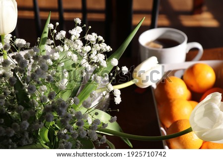 white flower bouquet at breakfast table sunlight shining on white tulips and baby breath flowers in rustic vase with morning coffee fruit dishes breakfast rustic kitchen meal with food and flowers sun