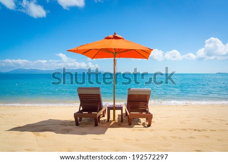 Two lounge chairs with sun umbrella on a beach Royalty-Free Stock Photo #192572297