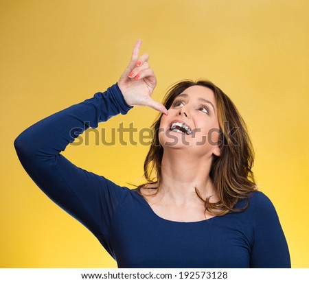 Closeup portrait young, silly, goofy woman, gesturing with hand thumb to go party, get drunk, hammered, wasted, isolated yellow background. Positive emotions, facial expressions, feeling, sign, symbol