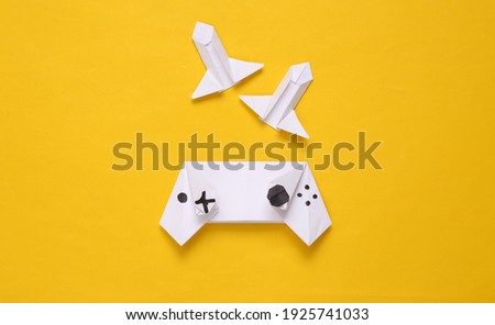Origami gamepad and rocket on yellow background