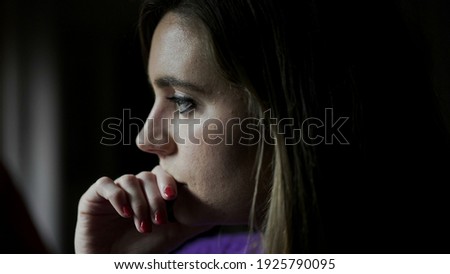 Anxious young woman standing by window concerned with life problems Royalty-Free Stock Photo #1925790095