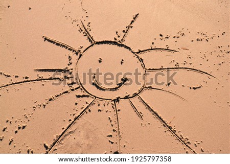 A smiling sun drawing on the sand
