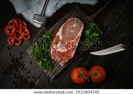 Raw new york beef steak cooking with ingredients on a wooden cutting board . Top view. 