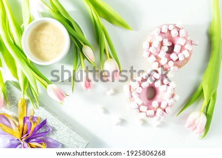 8 march with donuts, sweet donuts with tulips on a white background, top view, flatley