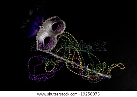 A Mardi Gras or constume party mask with beads on a black background