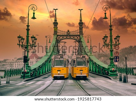 Two old yellows trams on the Liberty Bridge in Budapest. Architecture of Art Nouveau style.