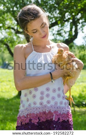 picture of beautiful brunette young woman having fun taking care of little red chicken happy smiling & looking at camera on white background