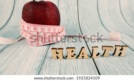 Fitness, Healthy Concept. Red apple with measuring tape isolated on blue background . Diet. Dietary nutrition. Text health. Selective focus.
