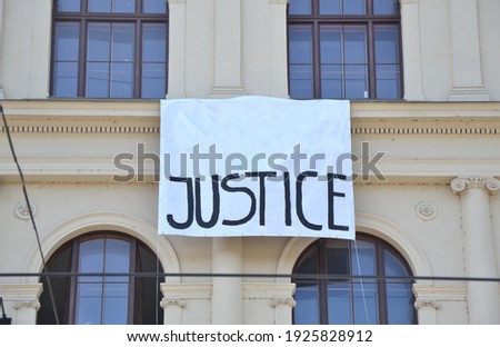 Word "JUSTICE" written on the white hanging banner hanging on a building